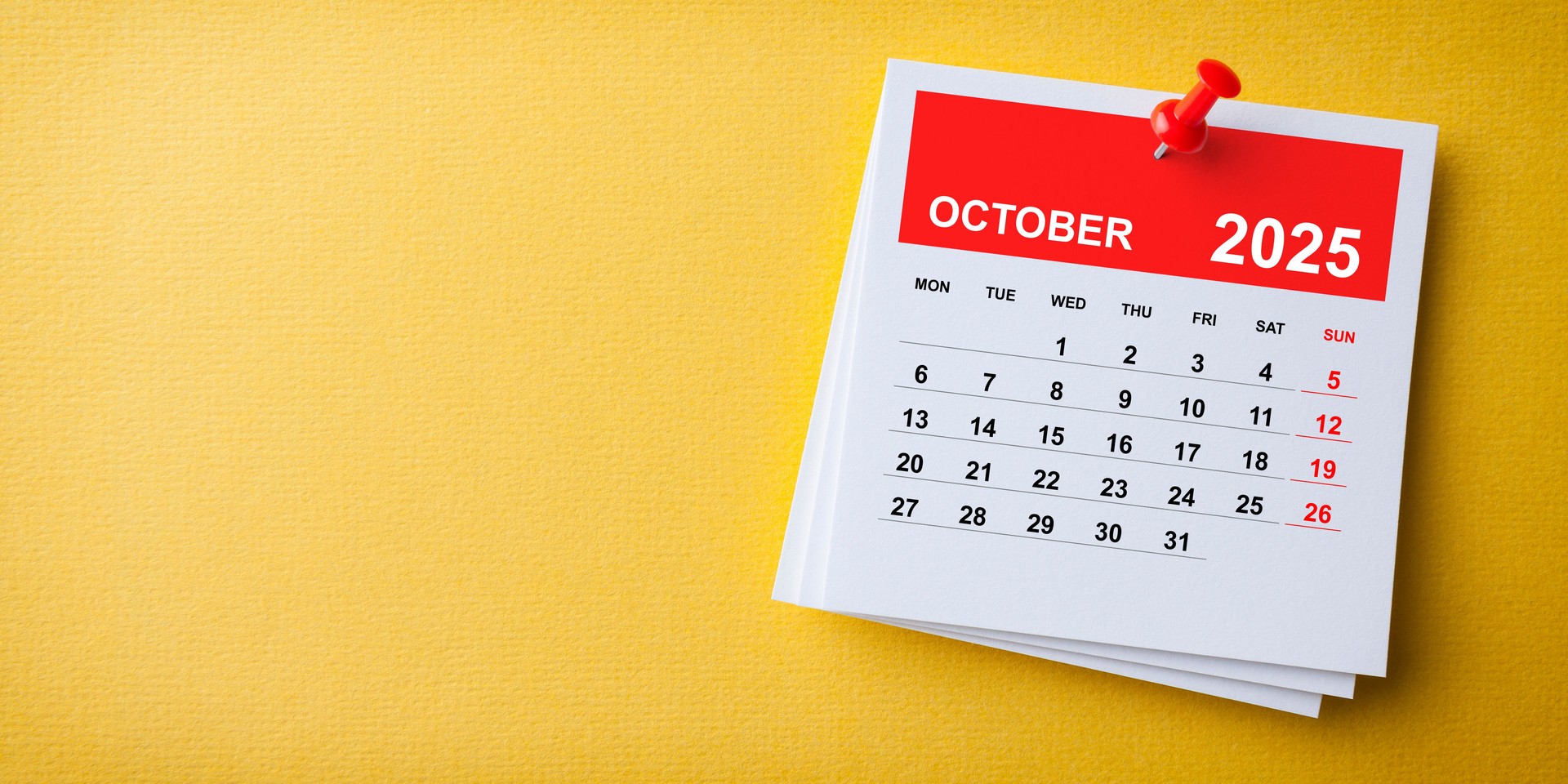 White Sticky Note With 2025 October Calendar And Red Push Pin On Yellow Background. Week starts on Monday.